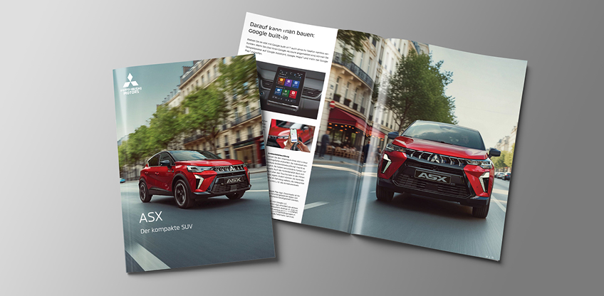 Auf grauem Hintergrund liegen eine geschlossene und eine aufgeschlagene Mitsubishi ASX Brosch&uuml;re; auf dem Cover ein roter Mitsubishi ASX auf einer Stadtstra&szlig;e mit B&auml;umen am Stra&szlig;enrand.
