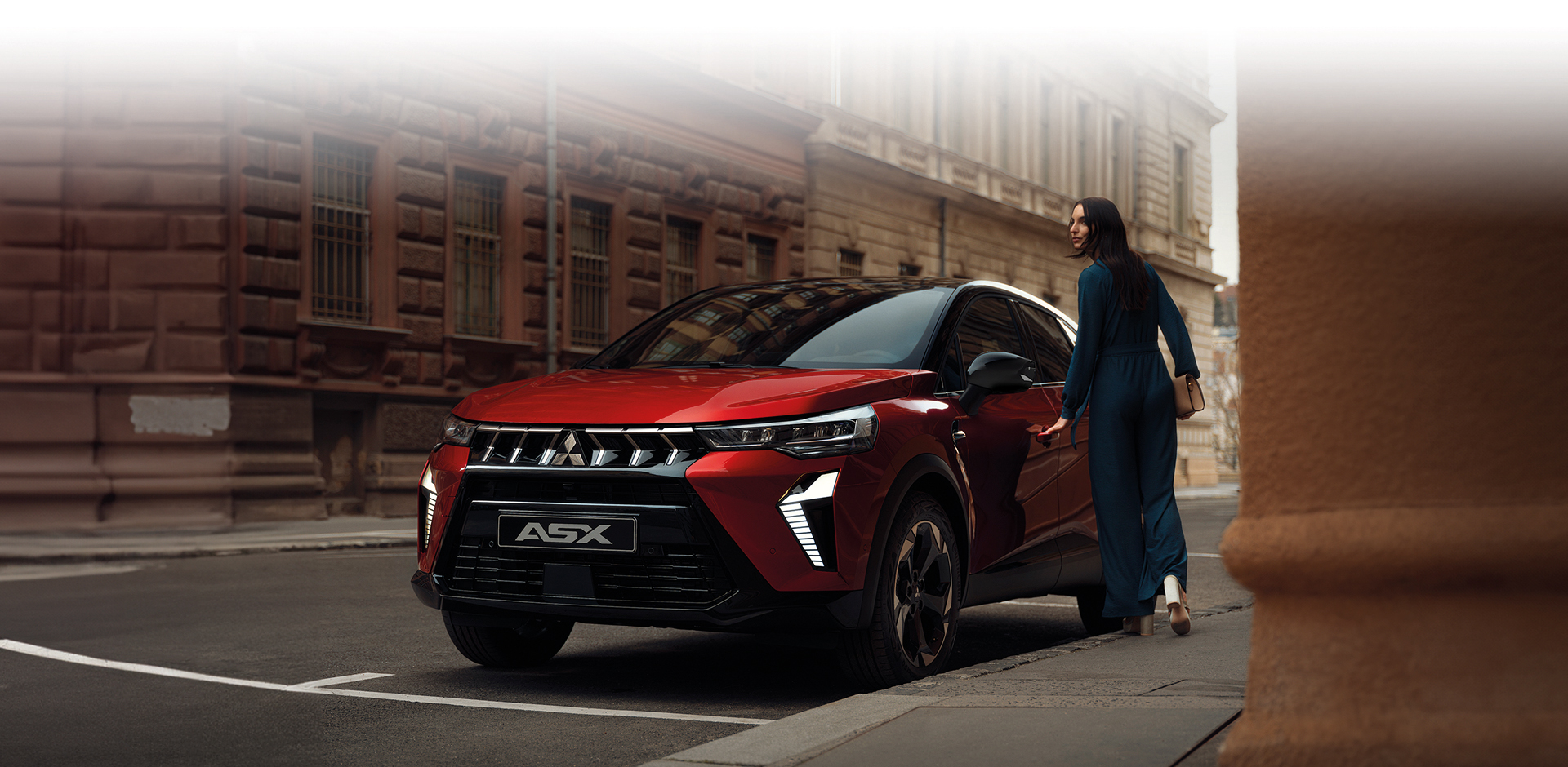 Roter Mitsubishi ASX SUV mit markanter Front steht in einer Stadtstra&szlig;e, eine Frau geht auf das Fahrzeug zu &ndash; Fokus auf dem modernen Au&szlig;endesign.