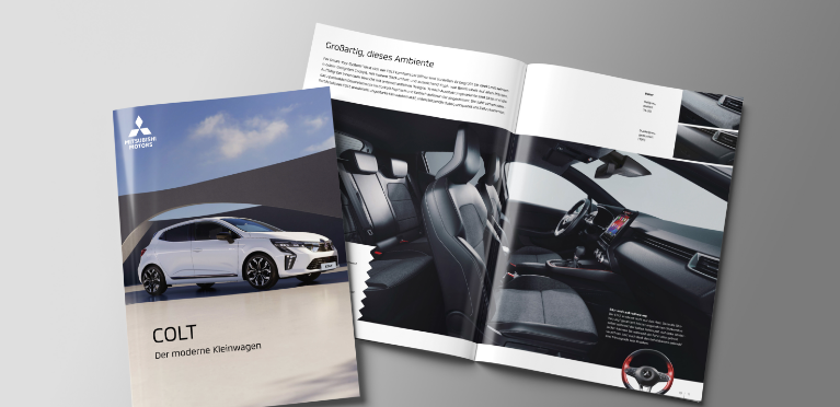 Die aufgeblätterte Broschüre des COLT liegt auf grauem Untergrund.