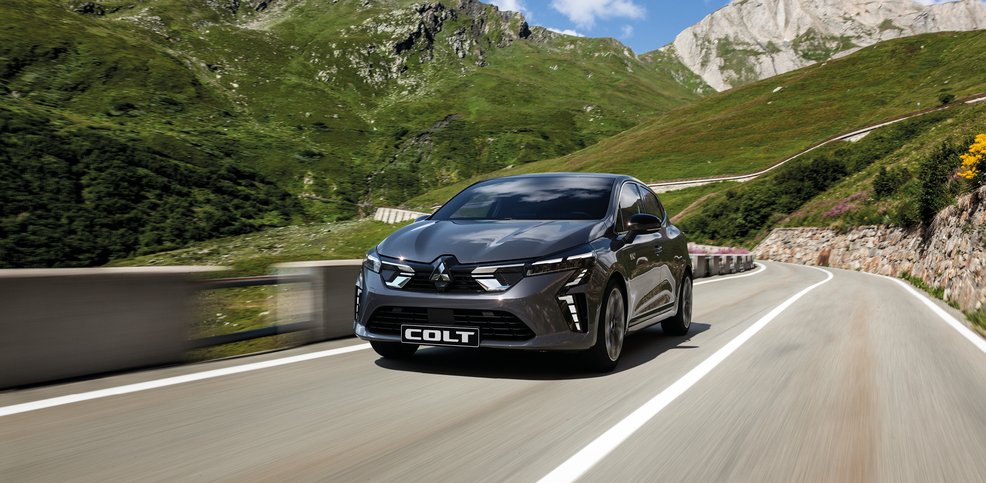 Ein grauer Mitsubishi COLT f&auml;hrt eine Bergstra&szlig;e entlang