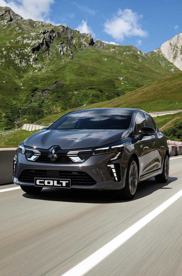 Ein grauer Mitsubishi COLT f&auml;hrt eine Bergstra&szlig;e entlang