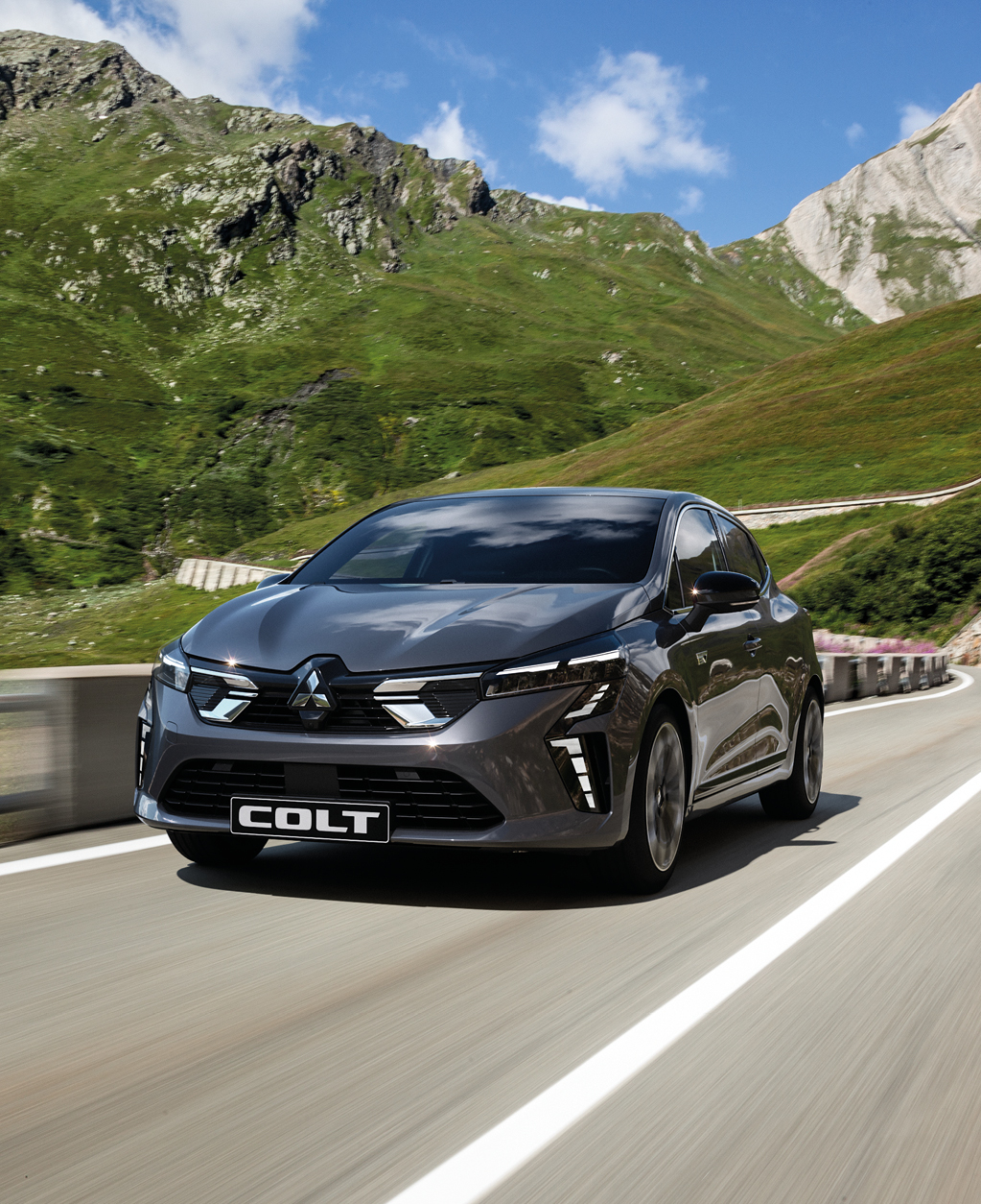 Ein grauer Mitsubishi COLT f&auml;hrt eine Bergstra&szlig;e entlang