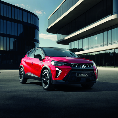 Roter Mitsubishi ASX Kompakt-SUV steht vor modernen B&uuml;rogeb&auml;uden auf einem offenen Platz &ndash; pr&auml;sentiert als moderne Alternative zum COLT.
