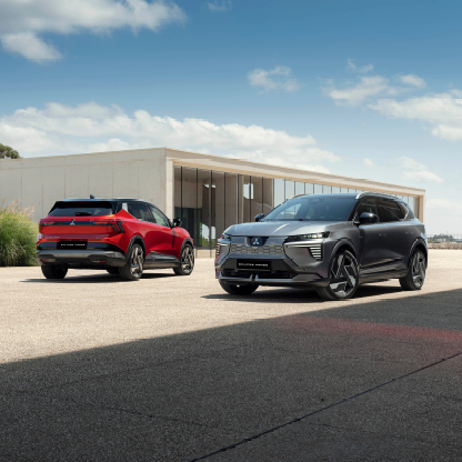 Zwei Mitsubishi Eclipse Cross Fahrzeuge in Grau und Rot stehen vor einem Geb&auml;ude mit moderner Architektur.