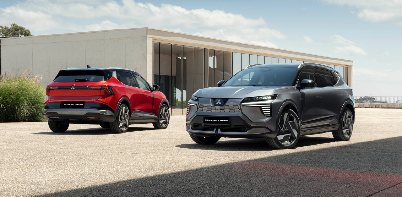 Zwei Mitsubishi Eclipse Cross Fahrzeuge in Grau und Rot stehen vor einem Geb&auml;ude mit moderner Architektur.