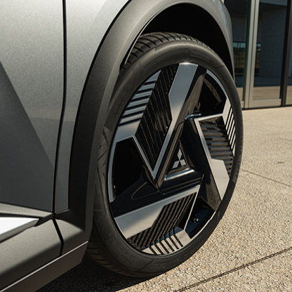 Ein grauer Mitsubishi Eclipse Cross ist aus der Heckansicht vor einem modernen Geb&auml;ude mit Fensterfront zu sehen.