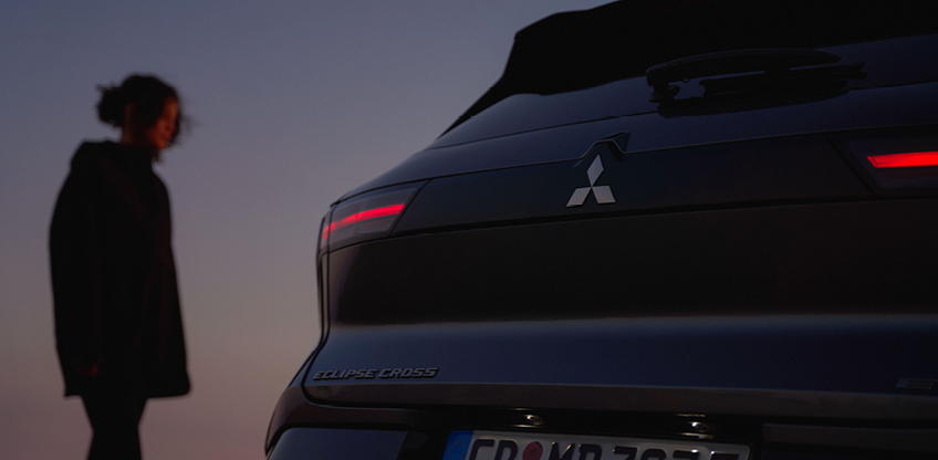 Eine Frau betrachtet das Heck des neuen Mitsubishi Eclipse Cross in der Dämmerung.