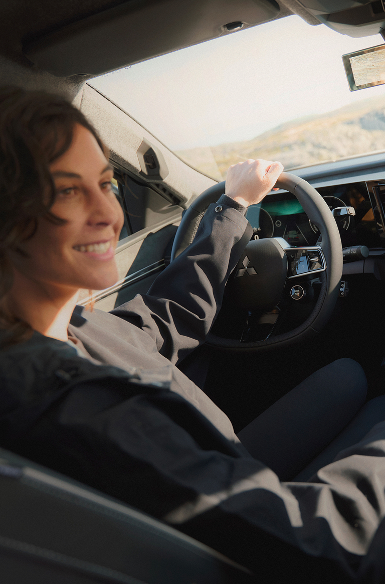 Eine Frau schaut auf dem Fahrersitz sitzend zu ihrem männlichen Beifahrer, auf dem Infotainment erkennt man die Fahreinstellung ECO.