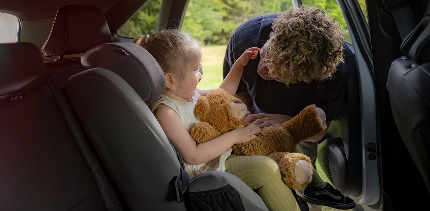 Vater schnallt seine Tochter im Kindersitz auf der Rückbank an