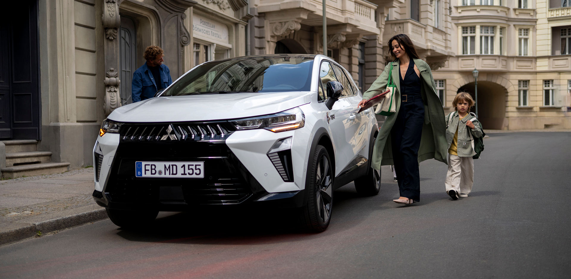 Frau mit Kind an der Hand läuft auf den parkenden Grandis zu