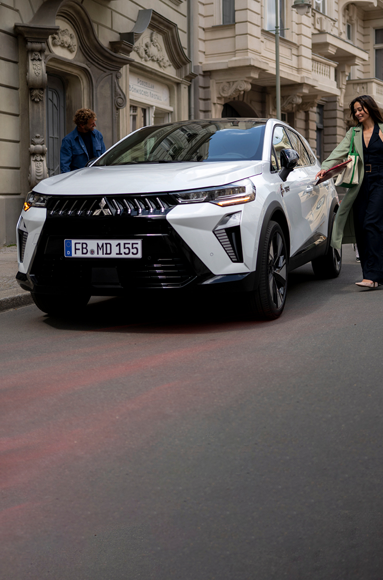 Frau mit Kind an der Hand läuft auf den parkenden Grandis zu