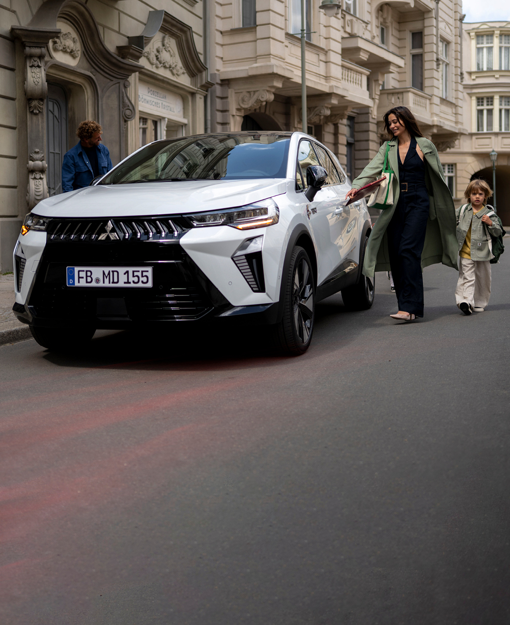 Frau mit Kind an der Hand läuft auf den parkenden Grandis zu