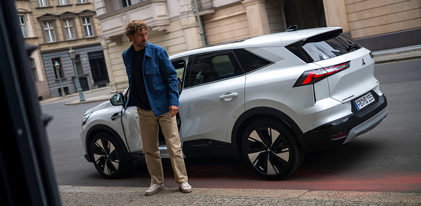 Ein Mann steht neben dem parkenden Grandis am Straßenrand