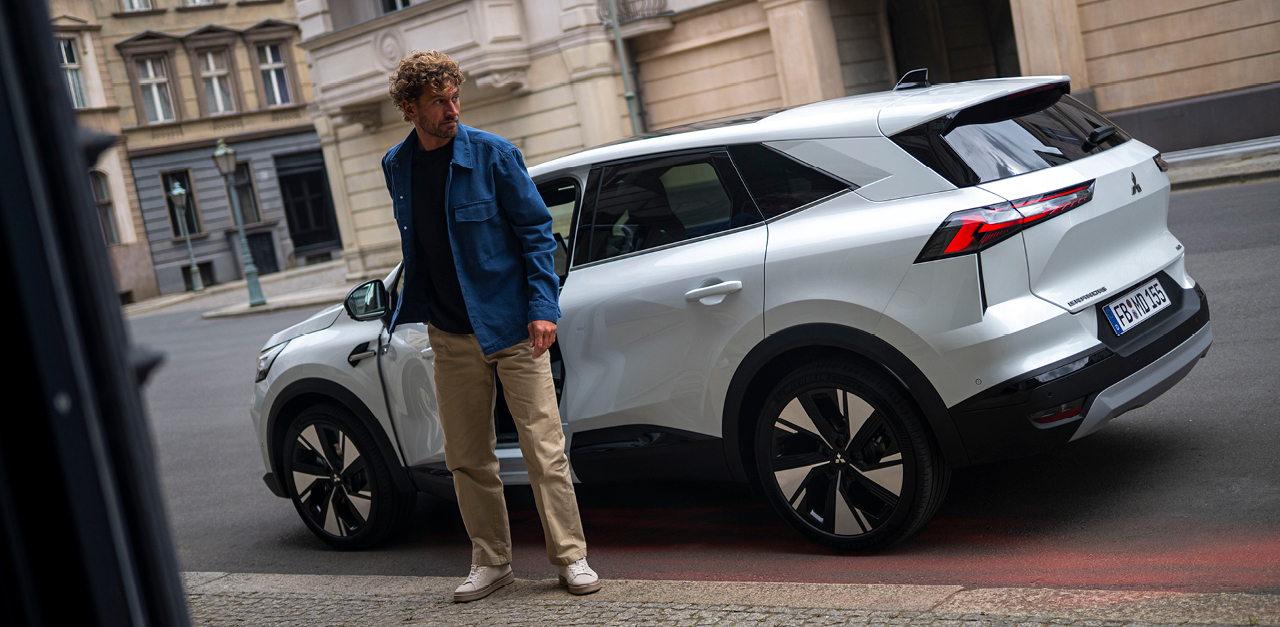 Ein Mann steht neben dem parkenden Grandis am Straßenrand