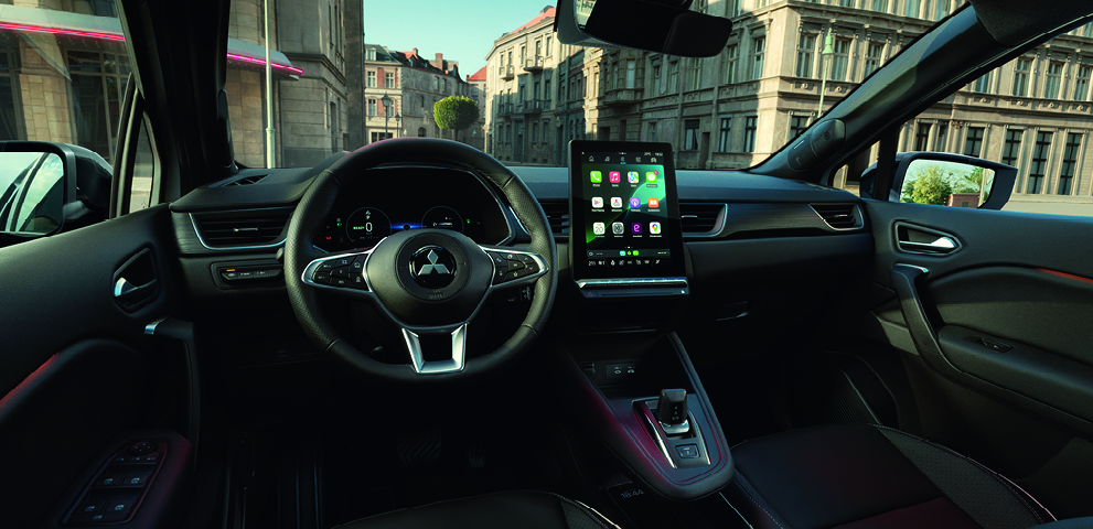 Modernen Innenraum eines Mitsubishi Grandis mit Multifunktionslenkrad, digitalem Cockpit und gro&szlig;em zentralen Touchscreen mit Apps, Blick nach au&szlig;en in eine Stadt.
