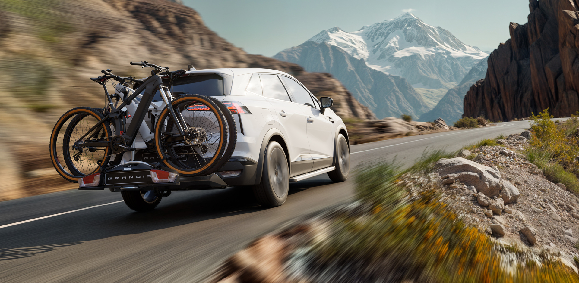 Der Mitsubishi Grandis mit Fahrrad-Hecktr&auml;ger beladen mit 2 Fahrr&auml;dern f&auml;hrt eine Gebirgsstra&szlig;e entlang.