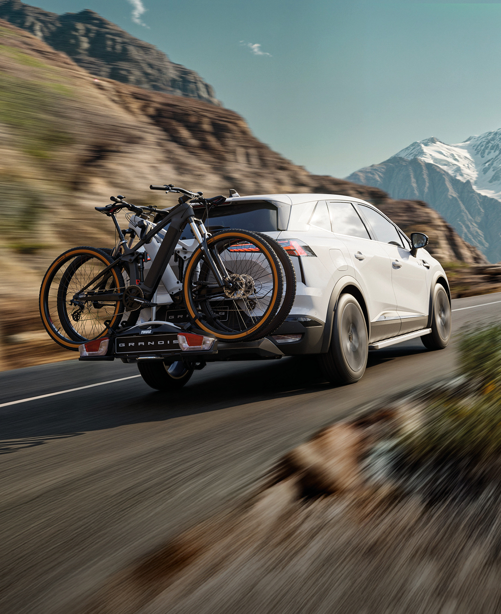 Der Mitsubishi Grandis mit Fahrrad-Hecktr&auml;ger beladen mit 2 Fahrr&auml;dern f&auml;hrt eine Gebirgsstra&szlig;e entlang.