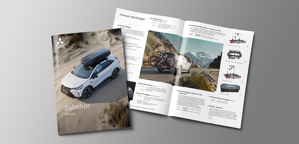 Geschlossene und ge&ouml;ffnete Zubeh&ouml;rbrosch&uuml;re f&uuml;r den Mitsubishi Grandis: Auf dem Titelbild f&auml;hrt das wei&szlig;e Fahrzeug mit montierter Dachbox durch eine sandige D&uuml;nenlandschaft. Die aufgeklappte Doppelseite zeigt Produktfotos und Beschreibungen von Autozubeh&ouml;r sowie ein gro&szlig;es Landschaftsbild mit einem Grandis auf einer Gebirgsstra&szlig;e und zwei Fahrr&auml;dern am Hecktr&auml;ger.
