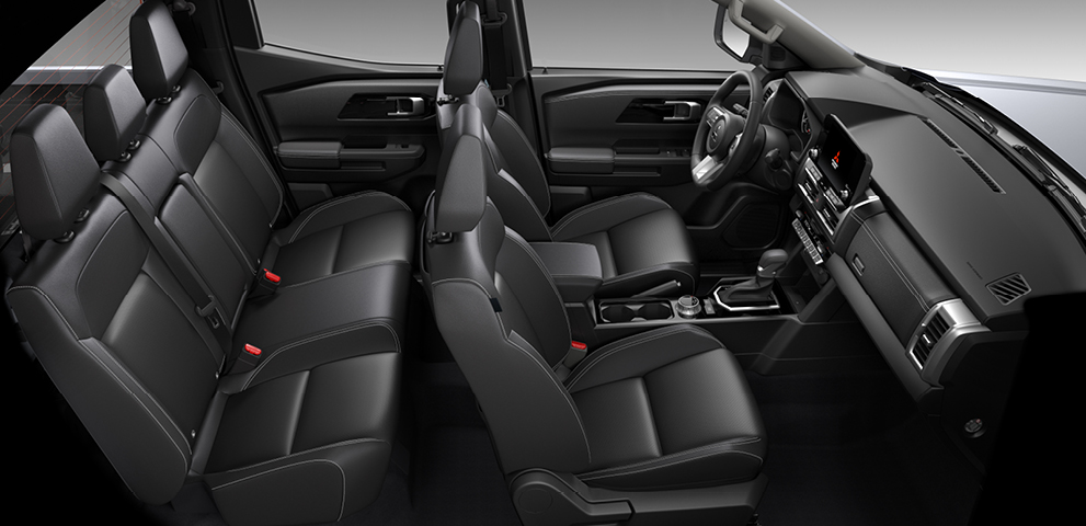 Blick in den schwarzen Innenraum eines Mitsubishi L200 mit drei Sitzreihen, gepolsterten Sitzen, Mittelkonsole mit Automatikschaltung und modernem Armaturenbrett.