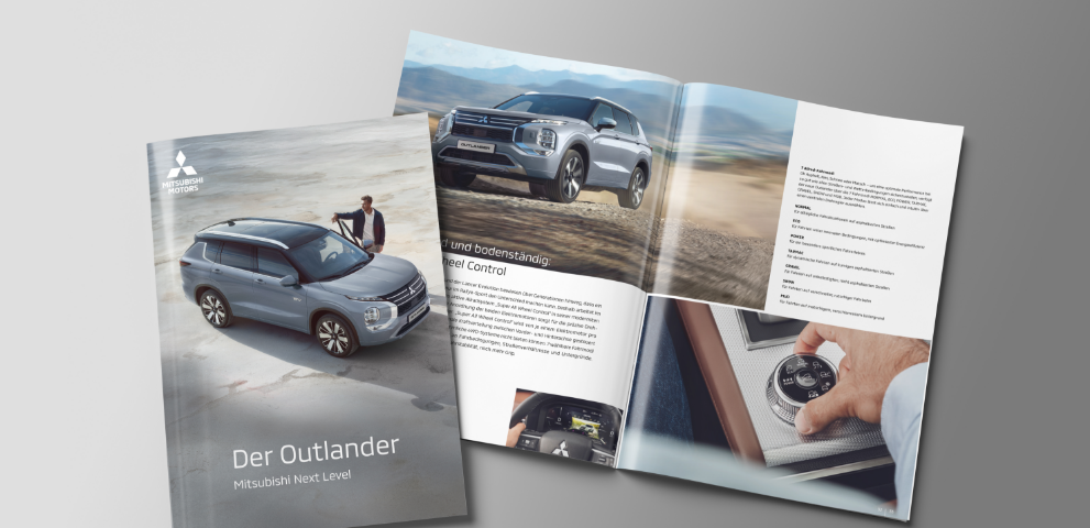 Die aufgeblätterte Broschüre des Outlander liegt auf grauem Untergrund.