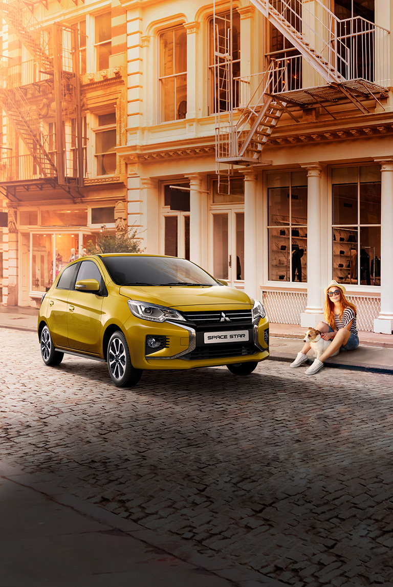 Frau mit Hund sitzt am Straßenrand neben einem parkenden Space Star