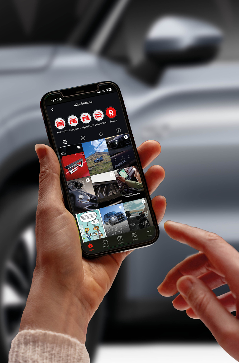 Nahaufnahme eines Smartphones, das das Instagram-Profil von MITSUBISHI MOTORS zeigt, vor dem unscharfen Hintergrund eines Fahrzeugs. 
