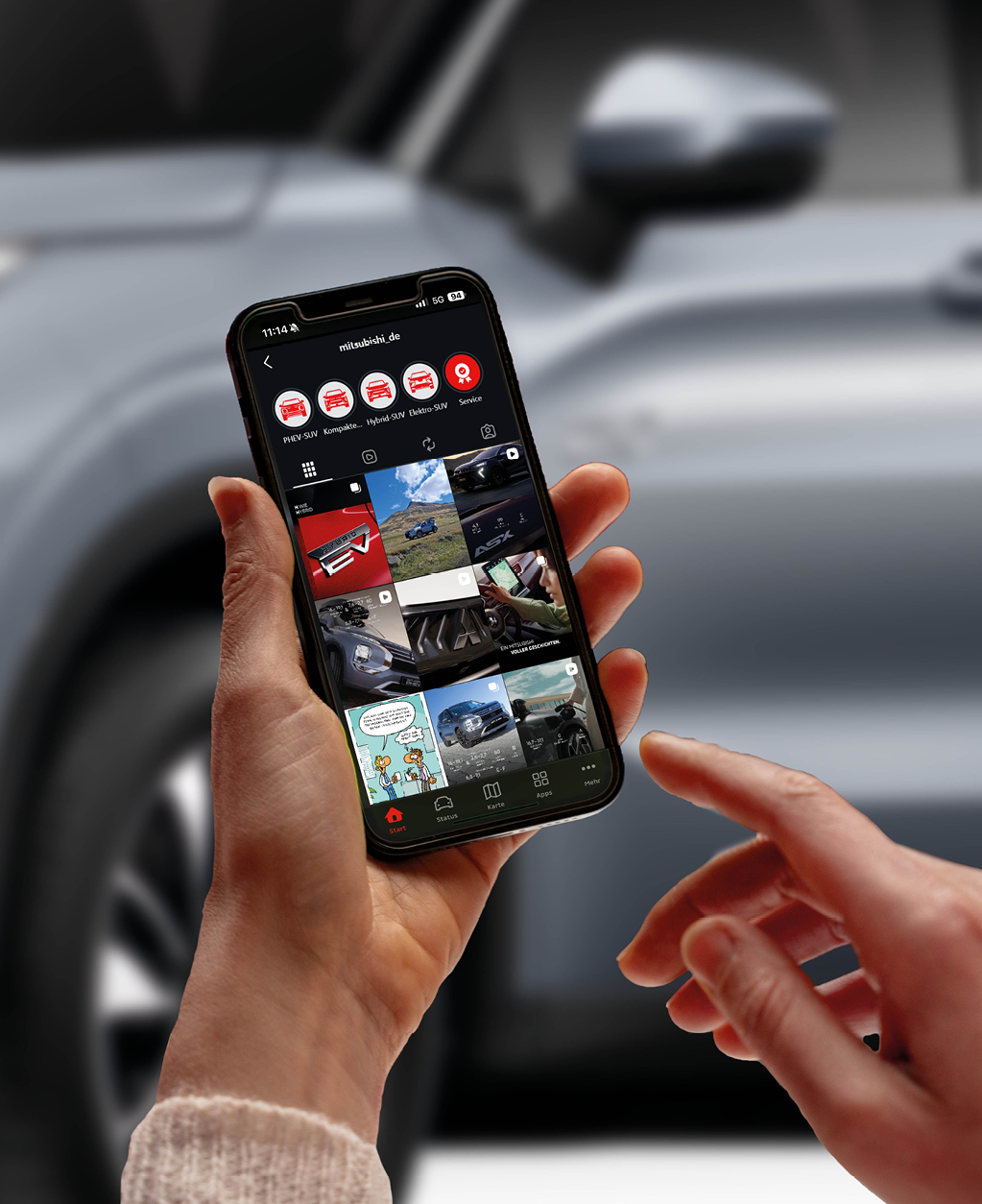 Nahaufnahme eines Smartphones, das das Instagram-Profil von MITSUBISHI MOTORS zeigt, vor dem unscharfen Hintergrund eines Fahrzeugs. 