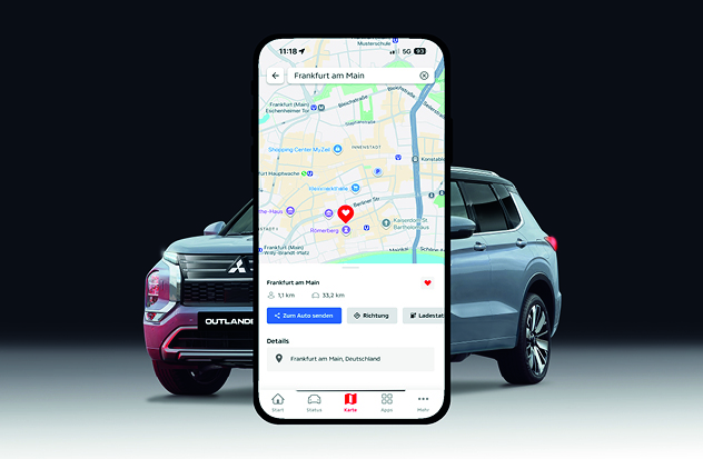 Ein gro&szlig;es Smartphone ist vor zwei stehenden Fahrzeugen platziert. Auf dem Display erscheint eine Kartenansicht der MITSUBISHI MOTORS App mit einem markierten Standort und Navigationsoptionen, begleitet vom Text, dass man Lieblingsorte suchen und ansteuern kann.